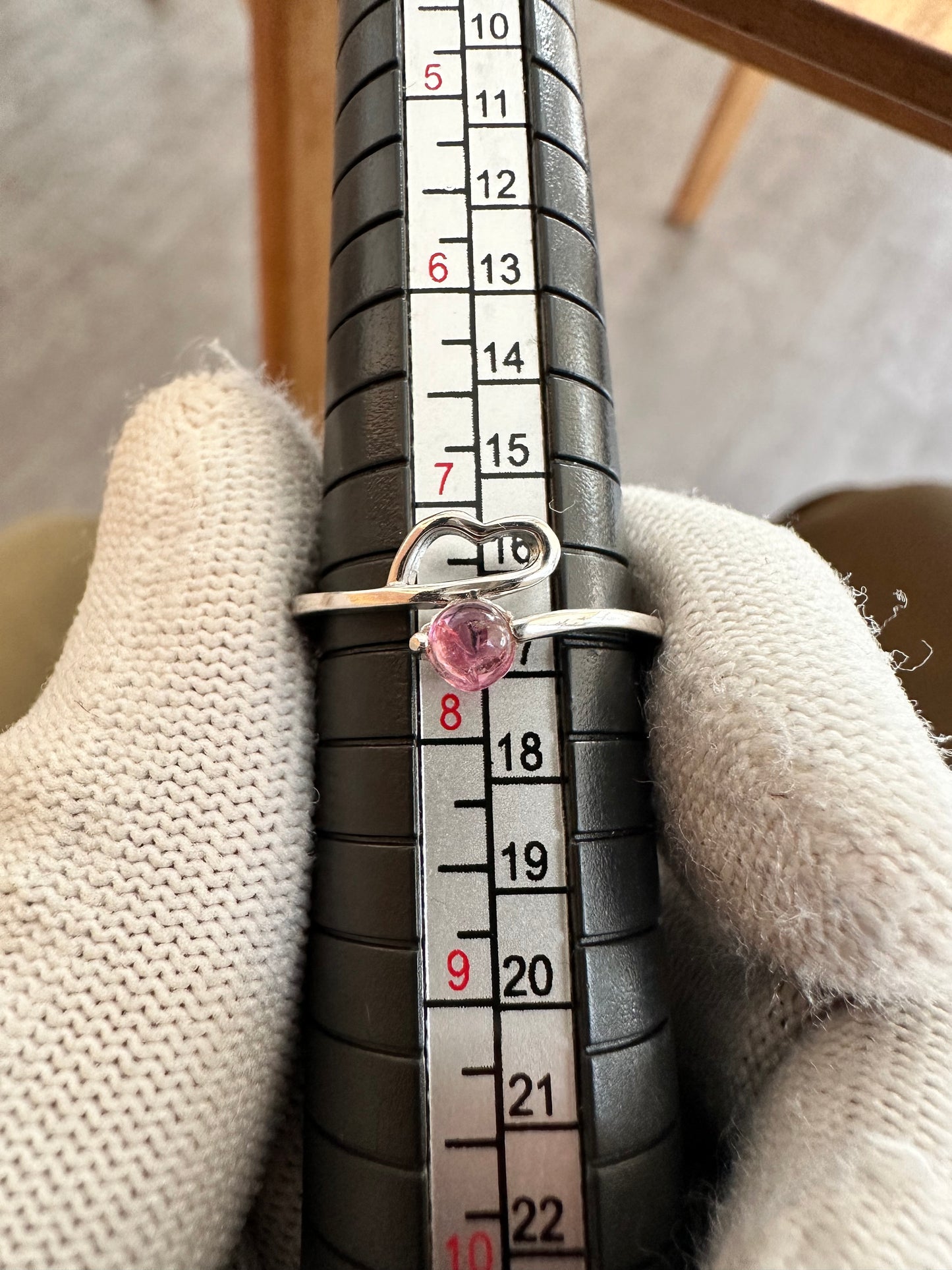 Silver ring with an oval-cut pink tourmaline gemstone,featuring a polished band with intricate detailing